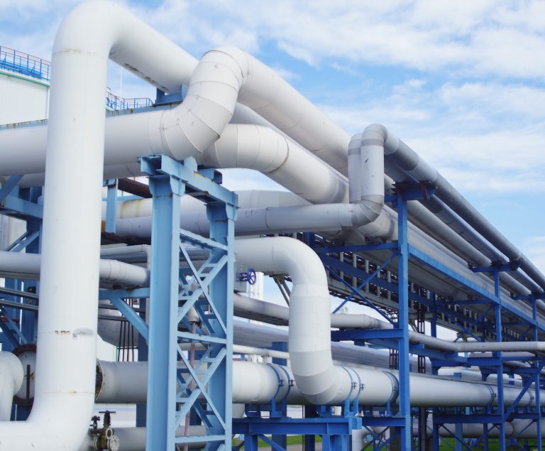 Industrial facility with large white pipes and steel supports